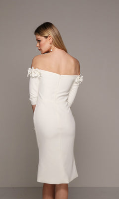 A woman with long blonde hair models the Alyce 70003, a knee-length semi-formal dress with 3D floral sleeve appliques, standing against a plain gray background and facing away from the camera.