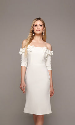 A woman models the Alyce 70003 knee-length semi-formal dress with off-the-shoulder sleeves and delicate 3D floral appliques along the neckline, set against a plain gray background.