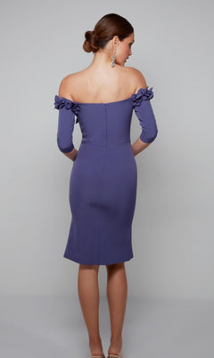 A woman stands with her back to the camera, wearing the Alyce 70003 knee-length semi-formal dress featuring off-the-shoulder 3D floral applique sleeves and paired with beige heels. Her hair is styled neatly in a low bun.