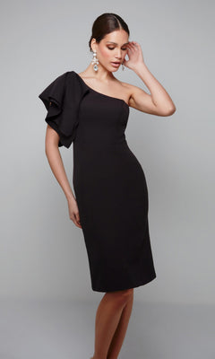 A woman models the Alyce 70005 knee length semi-formal dress in black, featuring a fitted silhouette and one-shoulder ruffle sleeve—an elegant choice for any stylish occasion.