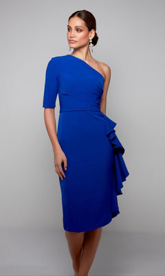 A woman poses against a plain grey background in the Alyce 70006 Knee Length Semi-Formal Dress, featuring a cobalt hue, one-shoulder design, and side ruffle detail.
