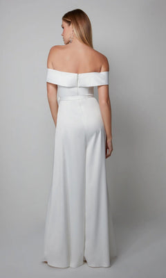 A woman models the Long Formal Jumpsuit: Alyce 70012, facing away from the camera in a white off-the-shoulder style against a plain gray background.