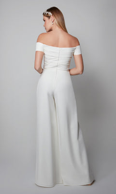A woman stands with her back to the camera, wearing the Alyce 70014 Long Formal Jumpsuit and a decorative headpiece, against a plain gray background.