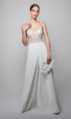 Woman models the Long White Jumpsuit: Alyce 70017 with a white lace bodice and wide-leg pants, holding a white floral clutch against a light gray background.