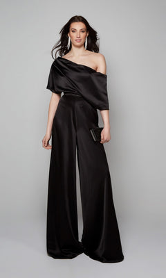 A woman wearing the Alyce 70019 Long Formal Jumpsuit with wide-leg pants holds a black clutch and stands against a plain gray background.