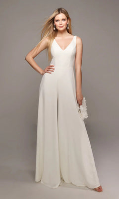 A woman stands against a plain grey background wearing the Long White Jumpsuit: Alyce 70021 with wide-leg pants, holding a small white clutch.