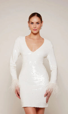 A woman in the Alyce 70027 knee-length white party dress, featuring long sleeves, sequins, a V-neckline, and feather-trim cuffs, stands against a plain background.