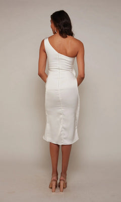 A woman faces away, wearing the Alyce 70038 knee-length white party dress and beige heels against a plain background.