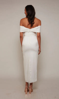 A woman stands with her back to the camera, wearing the Tea Length Formal Dress: Alyce 70041 and beige heels against a plain light-colored background.