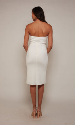 A woman faces away against a light background, wearing the Knee Length White Party Dress: Alyce 70048 and beige heeled sandals.