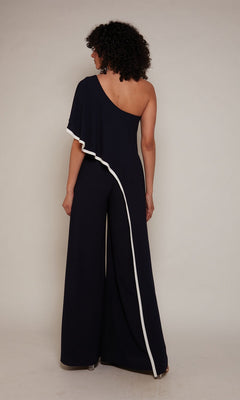 A person wearing the Long Formal Jumpsuit: Alyce 70049, a black one-shoulder style with white trim, stands facing away against a plain background.