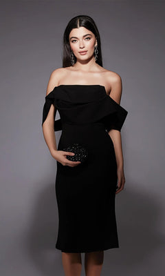 A woman in the black Alyce 70055 knee-length semi-formal dress and statement earrings poses against a gray background, holding a small black clutch.