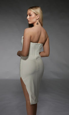 A woman poses elegantly in the Alyce 70058, a knee-length white party dress with a strapless, form-fitting design and side slit, set against a neutral background.