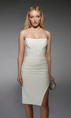 Woman wearing the Alyce 70058, a knee-length white party dress with a fitted bodice and thigh-high slit, holding a small glittery clutch against a plain gray background.