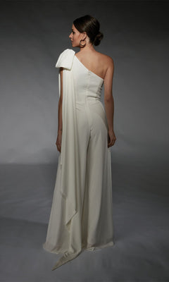 A woman stands facing away against a gray background in the Alyce 70065—an elegant white, one-shoulder long formal jumpsuit with draped detail, offering a chic alternative to a cocktail dress.