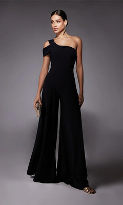 A woman poses against a plain gray background in the Alyce 70066 Long Formal Jumpsuit, featuring a one-shoulder design and wide-leg pants. She accessorizes with earrings and holds a small clutch.