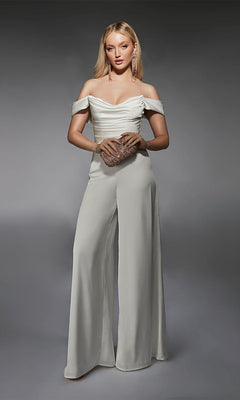 A woman poses against a gray background, wearing the Alyce 70071 long formal jumpsuit in ivory with wide-leg pants, and holds a sparkly clutch bag.