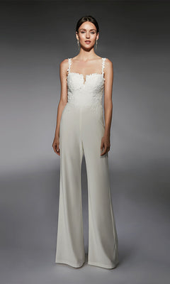 A woman faces forward, wearing the Long Formal Jumpsuit: Alyce 70073 in Diamond White with lace and floral embroidery on the bodice, set against a plain gray background.