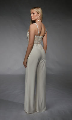 A woman models the Alyce 70074 long formal jumpsuit, showcasing a sleeveless white lace corset top and high-waisted wide-leg pants, set against a plain studio background.