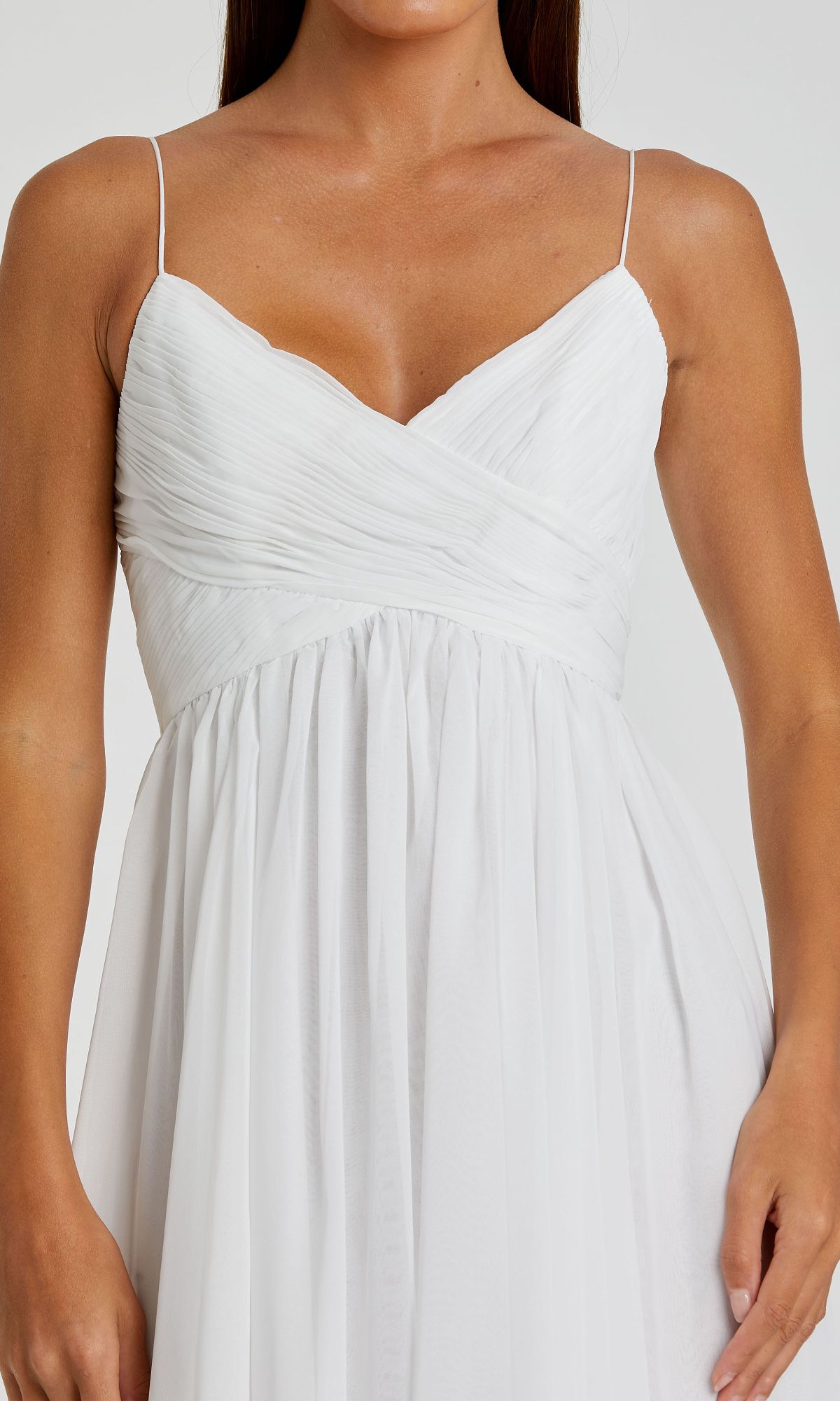 A woman wears the Mac Duggal 70099 A-Line Midi Wedding Guest Dress, a sleeveless white design with thin straps, ruched bodice, and a flowing tea-length skirt.
