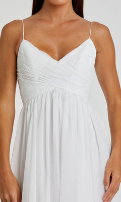 A woman wears the Mac Duggal 70099 A-Line Midi Wedding Guest Dress, a sleeveless white design with thin straps, ruched bodice, and a flowing tea-length skirt.