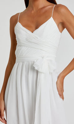 A woman wears the Mac Duggal 70100 Flowing Wide-Leg Formal Jumpsuit, featuring a sleeveless white design with thin straps, a V-neckline, ruched bodice, and fabric belt at the waist.