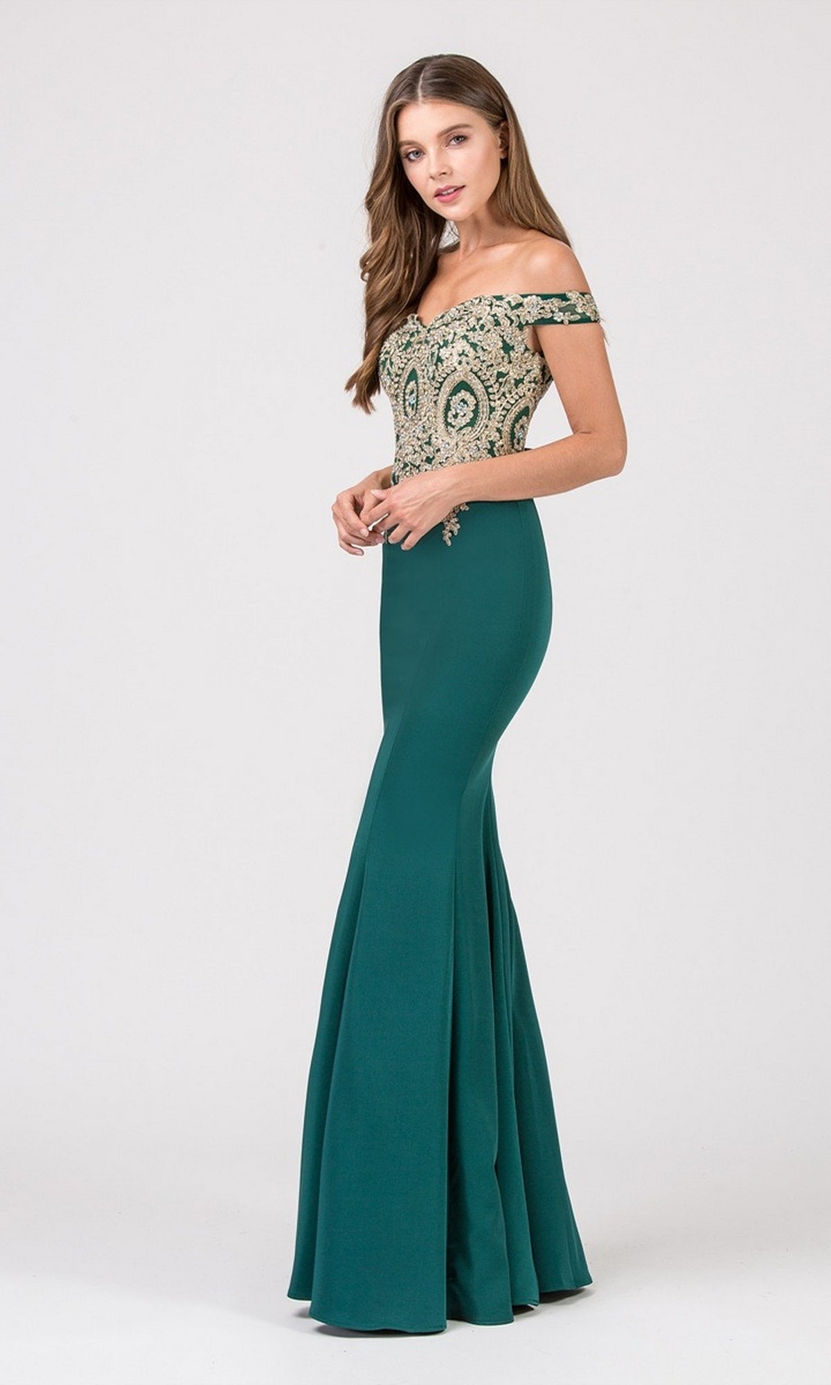 Woman in the Long Formal Dress: Eureka 7012, a navy/gold off-shoulder gown with mermaid skirt and metallic lace applique, stands against a plain light background.