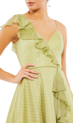 A woman wearing the Mac Duggal 70163 short green wedding guest dress, featuring a ruffled v-neck, subtle dotted pattern, and sleeveless design.