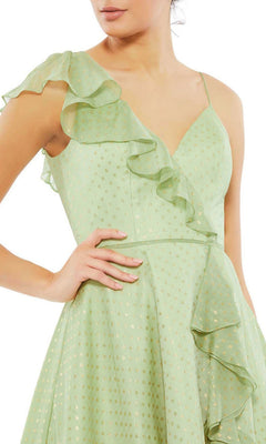 Woman wearing the Mac Duggal 70163 short green wedding guest dress with gold polka dots, ruffle details, and thin straps, posing with one hand on her waist.