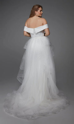 A woman models the Alyce 7020, a long white off-the-shoulder satin gown with a layered tulle skirt, standing and facing away against a gray background—ideal for wedding receptions or bridal events.
