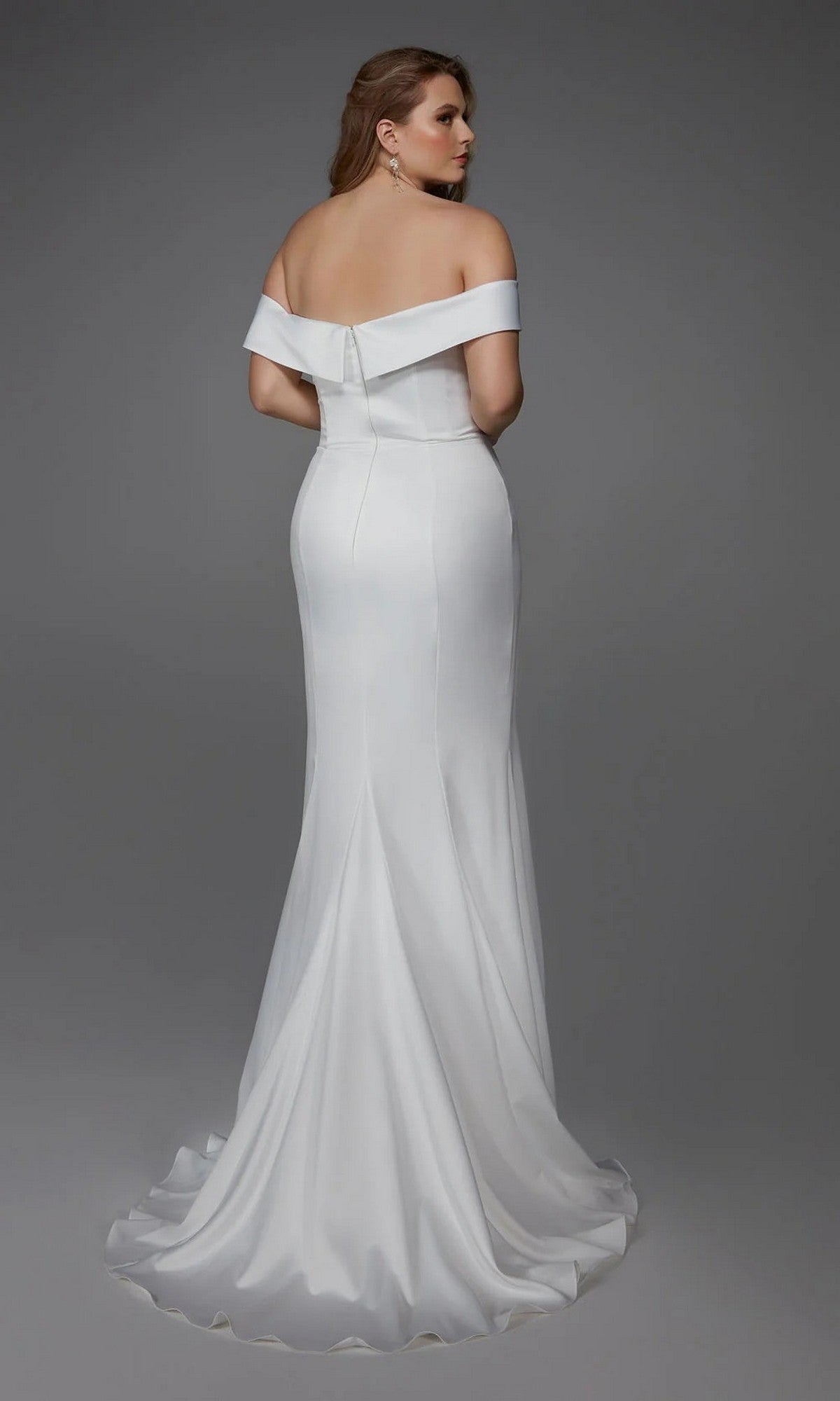 A woman faces away from the camera against a gray background, wearing the Alyce 7020—a fitted satin off-the-shoulder long white dress with a train—ideal for bridal events.
