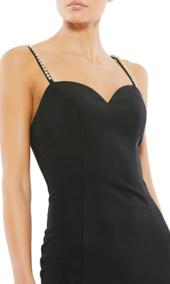 A woman wears the Long Formal Dress 70220 by Mac Duggal, a fitted black design with beaded trim, jewel-embellished straps, and a sweetheart neckline, shown cropped from shoulders to mid-thigh.