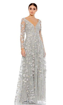 A woman wears the Mac Duggal 70224 Long Sleeve Long Formal Dress, a light gray embroidered maxi with sheer sleeves and floral lace appliqué, standing against a plain white background.