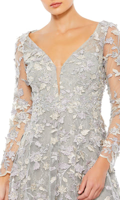 A woman wearing the Mac Duggal 70224 Long Sleeve Long Formal Dress in light gray lace, featuring floral embroidery and a deep V neckline.