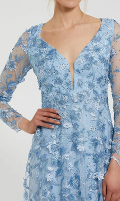 A person wearing the Mac Duggal 70224 long sleeve formal dress in light blue, featuring floral lace embroidery and a deep V-neckline, stands with one hand on their hip.