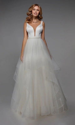 A woman wears the Alyce 7022 long ivory dress, featuring a sleeveless deep V neckline, fitted bodice, beaded waistband, and layered tulle skirt, standing against a plain gray background.