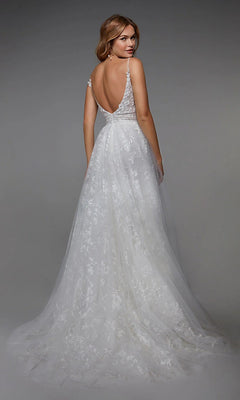 A woman stands facing away against a neutral background, wearing the Alyce 7036 Long White Dress with a sleeveless design, low back, lace detailing, and delicate floral appliqués.