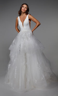 A woman wearing the Alyce 7040 long formal dress in ivory, featuring a sleeveless deep V-neck bodice and a layered tulle skirt adorned with floral lace.