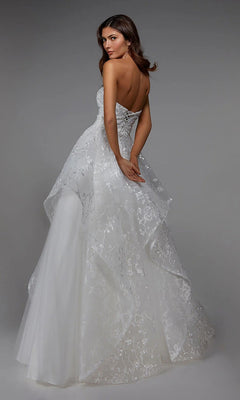 A woman faces away against a plain gray background, wearing the Alyce 7041 long formal dress—a strapless white ball gown featuring a layered, floral-embroidered skirt.