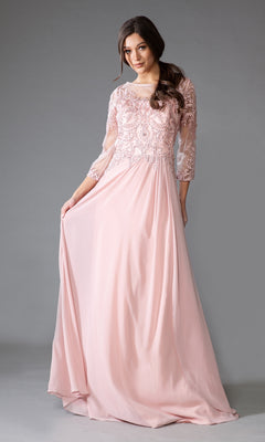 Woman modeling the Modest Long-Sleeve Mother-of-the-Bride Dress 7043 in light pink chiffon with lace bodice detailing and sheer three-quarter sleeves, standing against a gray background.
