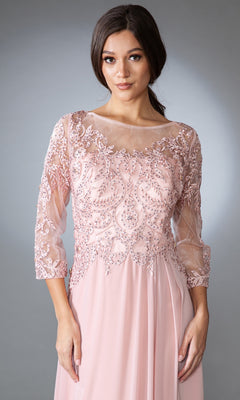 A woman models the Modest Long-Sleeve Mother-of-the-Bride Dress 7043, featuring a light pink chiffon design with lace and bead embellishments on the bodice and sheer three-quarter sleeves, set against a neutral background.