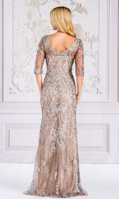A woman stands with her back to the camera wearing the Floral-Embroidered Long Sleeve Formal Dress 7045, a floor-length light brown gown featuring silver floral embroidery and sheer sleeves.
