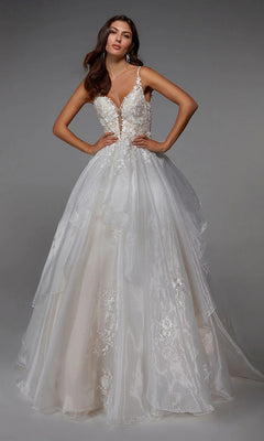 A woman stands confidently with hands on hips, wearing the Alyce 7047 long white dress in ivory/sand, featuring a sleeveless, floor-length silhouette, deep V-neckline, lace bodice, and layered tulle skirt.
