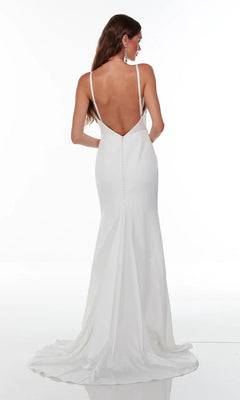 A woman wearing the Alyce 7051 long white dress—a modern bridal gown with a cowl neckline, deep V-back, thin straps, button details, and a small train—stands against a plain white background.