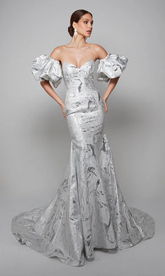 A woman poses in the Alyce 7055 long white dress in ivory/silver, featuring dramatic puffed sleeves and a fitted, flared skirt—a sophisticated mother-of-the-bride look—against a plain gray background.