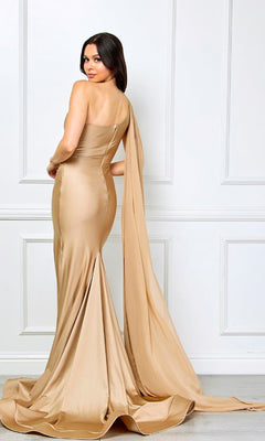A woman in the Amelia Couture 7056 one-shoulder long prom dress stands before a white paneled wall, looking over her shoulder as the elegant gown's draped train flows behind her.