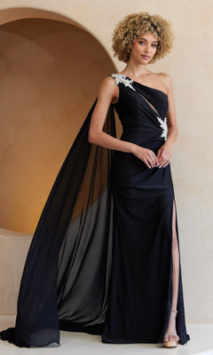 A woman stands against a neutral background wearing the Amelia Couture 7056, an elegant one-shoulder long prom dress featuring a draped cape, floral embellishments, and a thigh-high slit.