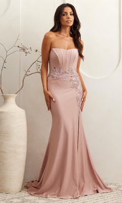 A woman in the Amelia Couture 7057 strapless corset prom dress with sequin lace appliques stands beside a tall vase with branches against a light background.