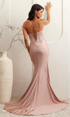 A woman stands with her back to the camera in a minimalist setting, wearing the Amelia Couture 7057 strapless corset prom dress in blush pink, adorned with sequin lace appliques and floral embroidery.