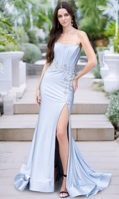 A woman stands outdoors on steps wearing the Amelia Couture 7057 Strapless Corset Prom Dress, featuring sequin lace appliques and a thigh-high slit.